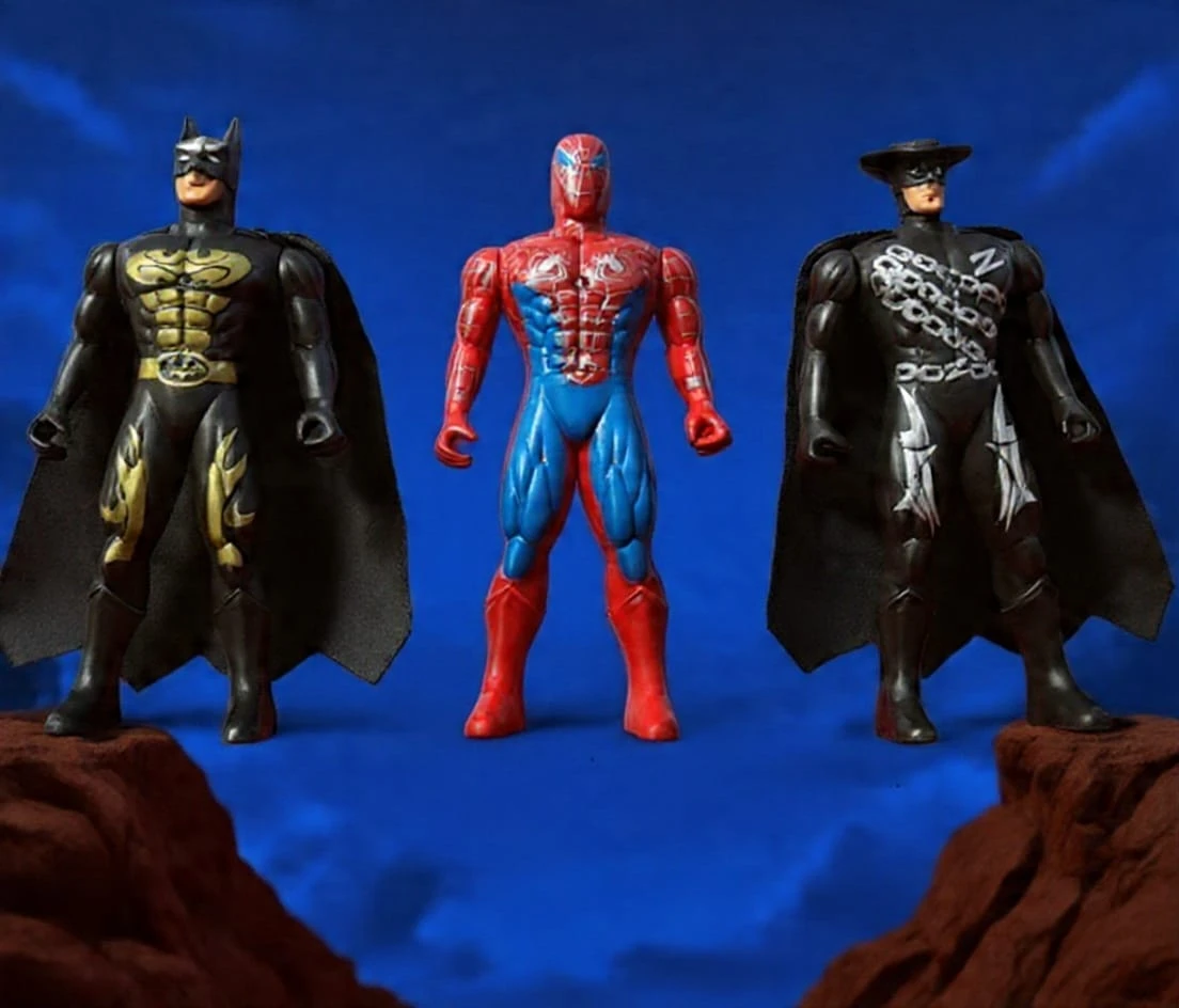 The image shows three superhero-style action figures standing against a vivid blue backdrop: